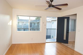 A room with a ceiling fan and a door leading to a balcony.